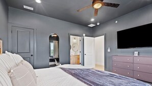 A bedroom with a bed, a dresser, a ceiling fan, and a television. - Lux Lake View: Sleeps 12+, Hot Tub, Game Room, Theater, Fire Pit (Branson)