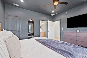 A bedroom with a bed, a dresser, a ceiling fan, and a television. - Lux Lake View: Sleeps 12+, Hot Tub, Game Room, Theater, Fire Pit (Branson)