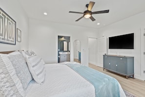 A bedroom with a bed, a ceiling fan, a TV, and a dresser. - Lux Lake View: Sleeps 12+, Hot Tub, Game Room, Theater, Fire Pit (Branson)