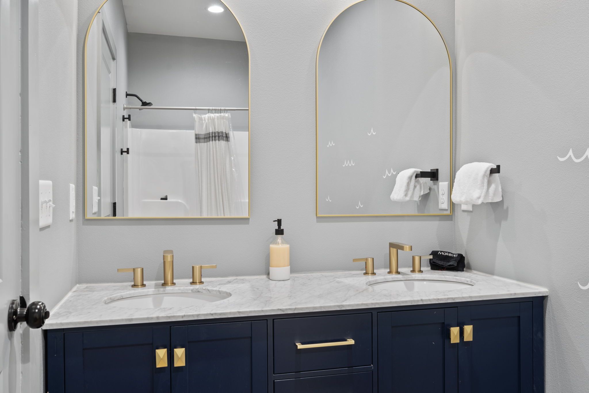 A bathroom with two sinks, a mirror, and a towel rack.
