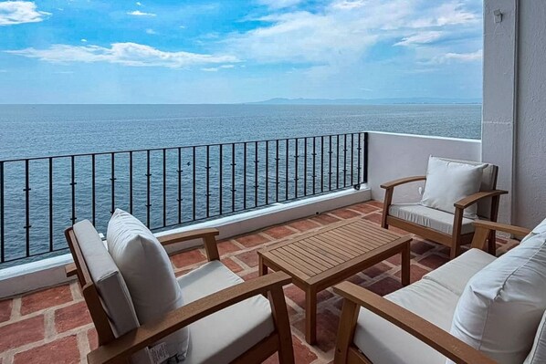 Ein Balkon mit Meerblick, ausgestattet mit einem Tisch und zwei Stühlen.