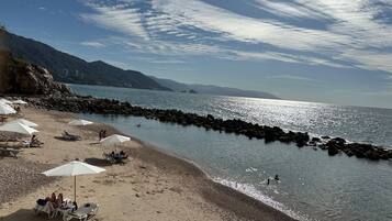 A beach with umbrellas, lounge chairs, and rocky shorelines.