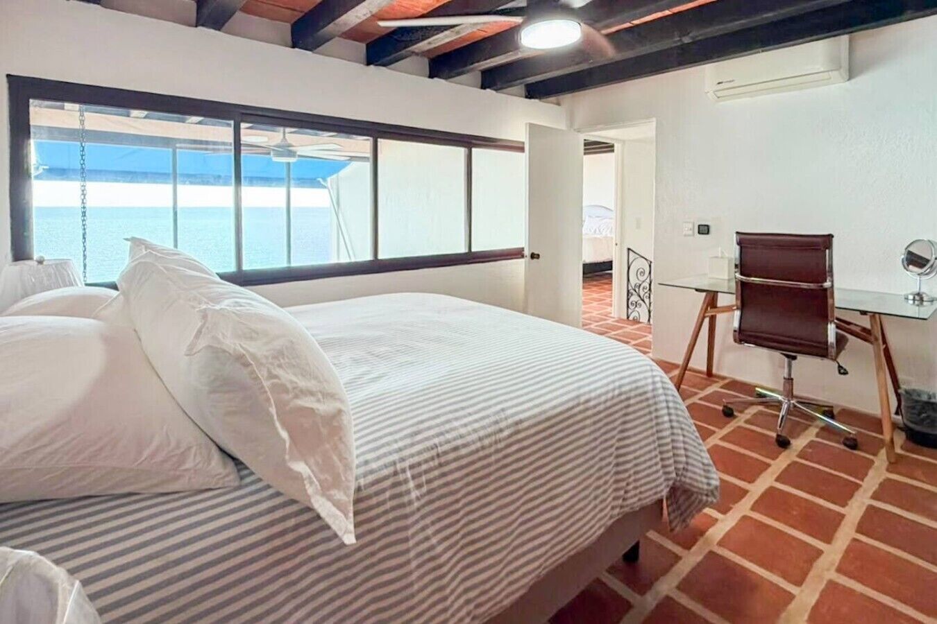 Une chambre d’hôtel avec un grand lit, un bureau et une vue sur la mer.