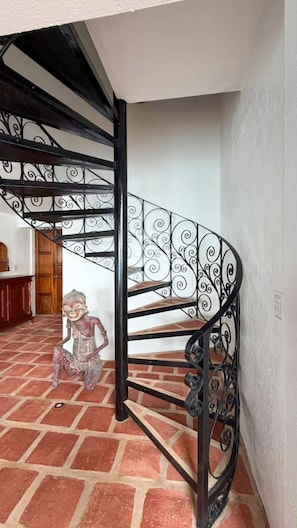 Una escalera de caracol con barandales de metal ornamentados y piso de ladrillo.