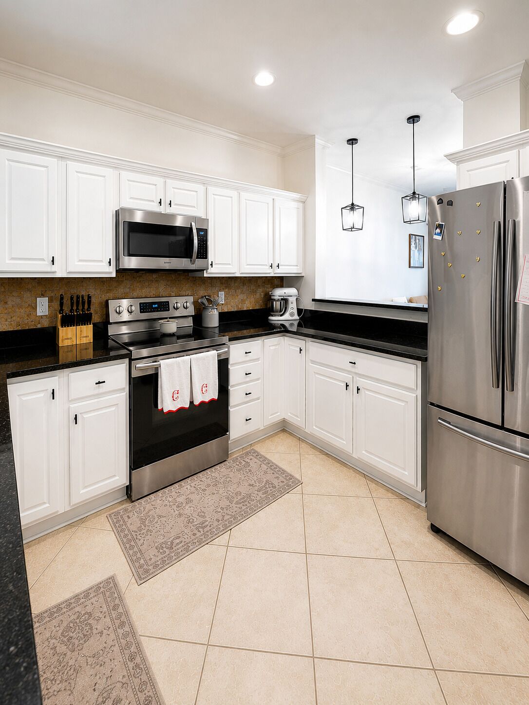 A modern kitchen with white cabinets, stainless steel appliances, and a patterned rug.