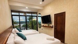 Een slaapkamer met twee bedden, een plafondventilator, een televisie en een groot raam met uitzicht.
