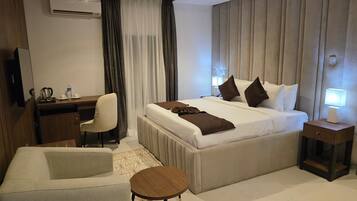 Une chambre d’hôtel comprenant un lit, une table de chevet, un bureau, une chaise et une petite table ronde.