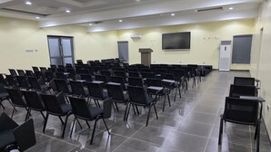 Un salón de conferencias con filas de sillas y un atril.