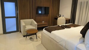 A hotel room with a bed, a sofa, a TV, a desk, and a chair.