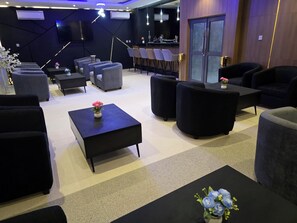 A modern lounge area with sofas, a coffee table, and a bar counter. - Movela Hotels Limited (Warri)