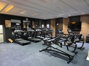 Un gimnasio con cintas de correr, elípticas y bancos de pesas.