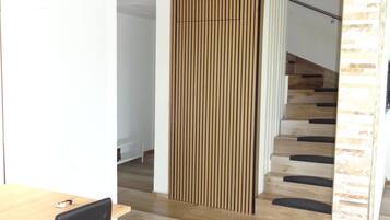 Un intérieur moderne agrémenté d’une cloison en bois, d’un escalier avec des marches en bois et d’un coin repas comprenant une table et des chaises.