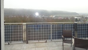 Un balcón con vistas a un panel solar y un edificio lejano.