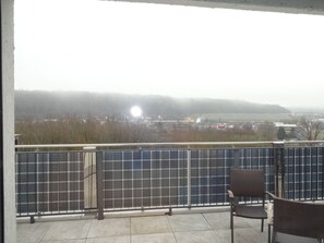 A balcony with a view of a solar panel array and a distant building.