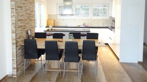 Una cocina moderna con una isla central, sillas negras y una mesa de comedor.