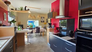Una cocina moderna con comedor, paredes rojas y vistas al exterior.