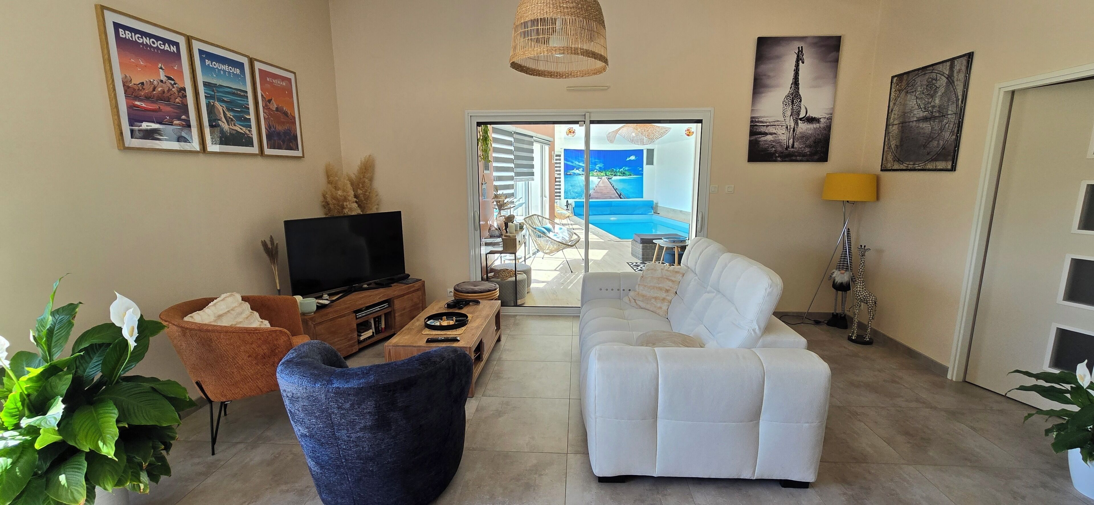A living room with a television, sofa, and a view of a pool through a glass door.