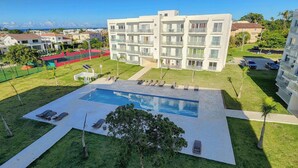A modern building with a swimming pool, sun loungers, and a view of the sea. -     Luxury Ocean View Condo in Sosua Ocean Village (Sosúa)