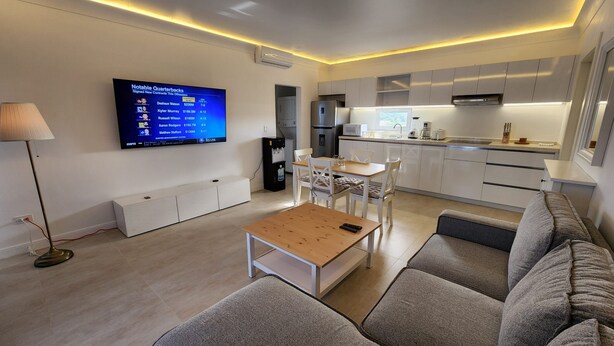 A modern living room with a flat-screen TV, a sofa, a coffee table, and a dining area with chairs. -     Luxury Ocean View Condo in Sosua Ocean Village (Sosúa)