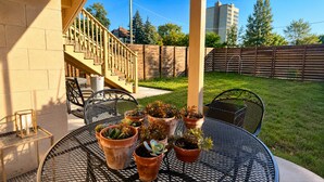 An outdoor patio with a round metal table, several potted plants, a chair, and a staircase leading to a covered area. - Wonderful two story, 2-bedroom apartment with AC in vibrant Detroit (Detroit)
