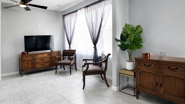 A living room with a television, wooden furniture, a large plant, and a window with sheer curtains. - Wonderful two story, 2-bedroom apartment with AC in vibrant Detroit (Detroit)