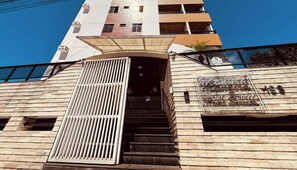 A building with a stone facade, a gated entrance, and a sign indicating a home service business. - LM Manaira Home Service (João Pessoa)