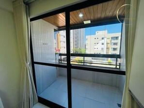 Un balcón con vistas a edificios, piso de baldosas y un cartel que indica prohibido fumar.
