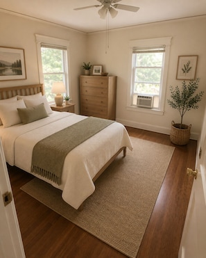 A bedroom with a bed, dresser, nightstand, lamp, window, and a ceiling fan.