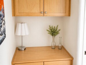 Een houten tafel met een lamp en twee glazen vazen met planten.