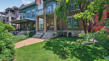 Una hilera de casas de ciudad con porches delanteros, césped y un árbol.