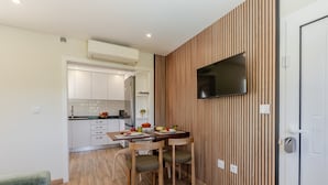Una cocina moderna con armarios blancos, horno empotrado y comedor con mesa y sillas de madera.