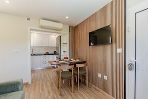 Eine moderne Küche mit weißen Schränken, einem eingebauten Ofen und einem Essbereich mit einem Holztisch und Stühlen.