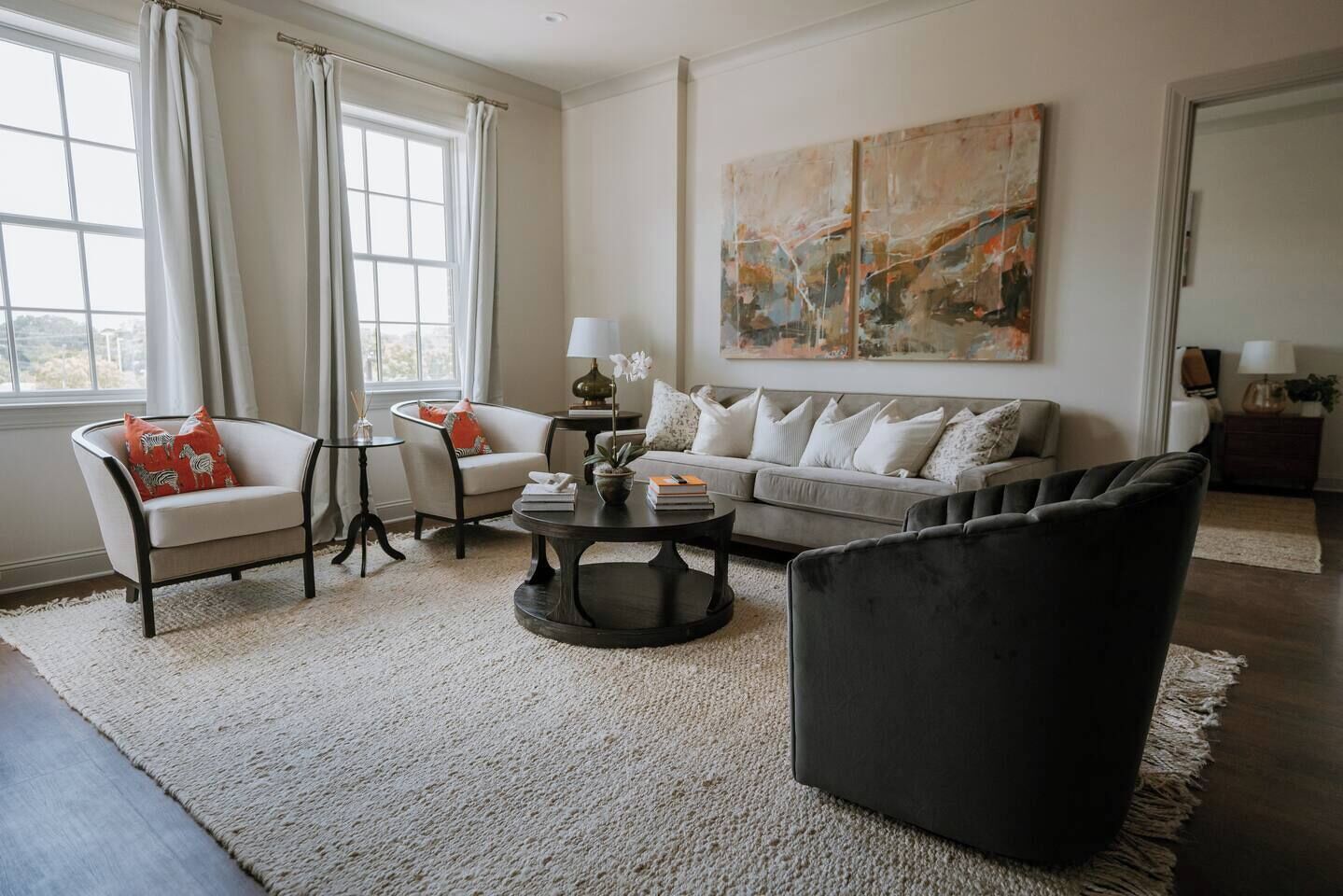 A living room with a sofa, armchairs, a coffee table, and a rug.