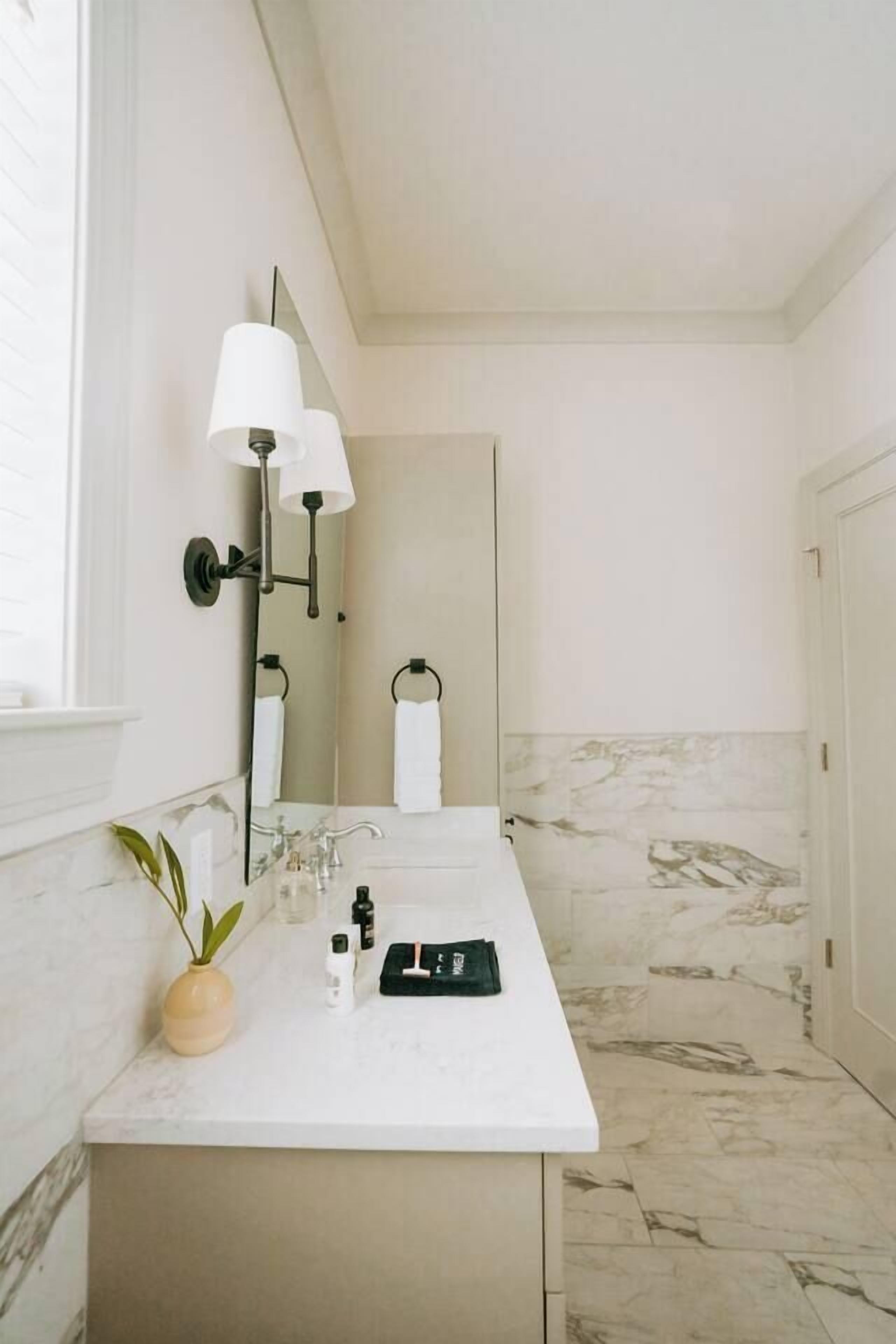 A bathroom with a white countertop, a mirror, a towel rack, and a marble floor.