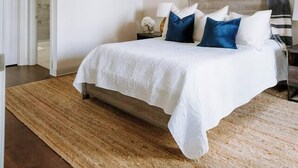 Ein Schlafzimmer mit einem Bett, einem Deckenventilator, einem Nachttisch und gerahmten Bildern an der Wand.