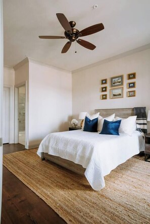 A bedroom with a bed, a ceiling fan, a nightstand, and framed pictures on the wall. - Lovely 2BR · Williams-Brice & Fort Jackson (Columbia)
