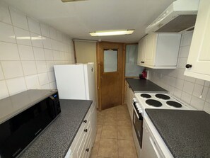 A kitchen with white cabinets, a microwave, a refrigerator, a stove, and a tiled floor. - Charming flat for short-term rent on a quiet,well-kept street close to Hyde Park (London)
