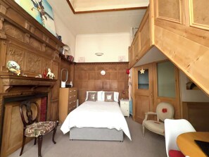 Ein Schlafzimmer mit Bett, Stuhl, Kommode und Spiegel.