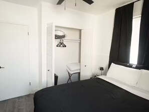 A bedroom with a bed, a closet, a chair, and a window with curtains.