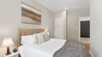 A bedroom with a bed, bedside lamp, and a painting on the wall.