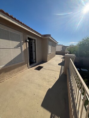 A residential building with a covered balcony, a garage door, and a clear sky.