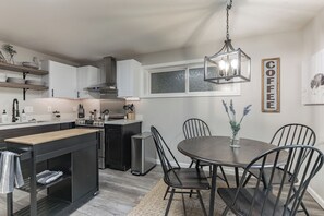 A modern kitchen with a central island, a dining area with a round table, and a hanging light fixture. - Peaceful 1-bedroom apartment with private entry in charming Snohomish (Snohomish)