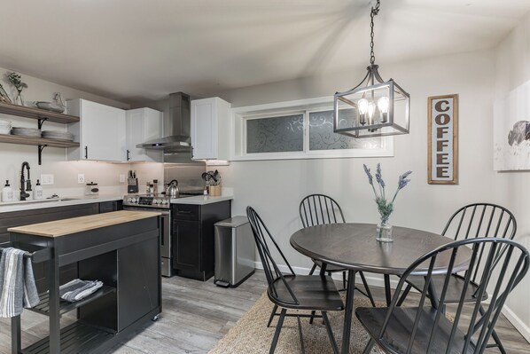 Uma cozinha moderna com uma ilha central, uma área de jantar com mesa redonda e um lustre.