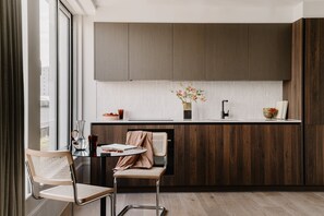 Une cuisine moderne avec des meubles en bois, un plan de travail blanc et une fenêtre agrémentée de rideaux.