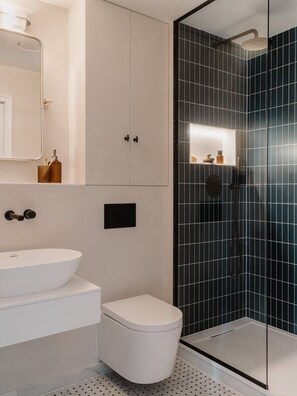 A modern bathroom with a white sink, toilet, and a glass-enclosed shower area. - Fulham Residences Seven (London)