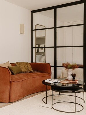 Ein Wohnzimmer mit braunem Sofa, einem Glastisch und einem großen Spiegel.