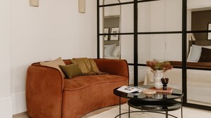 A modern living room with a brown sofa, a glass coffee table, and a view through a large window. - Fulham Residences Seven (London)