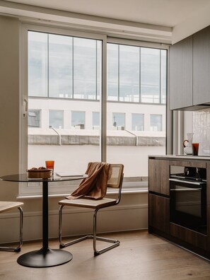Eine moderne Küche mit einem großen Fenster, einem Esstisch mit Stühlen und einer Küchenzeile.