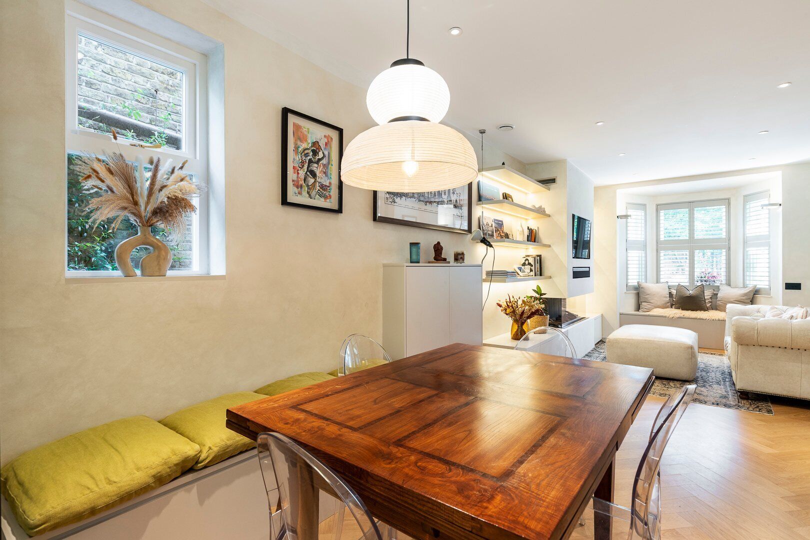 Un comedor moderno con una mesa de madera, sillas y una lámpara colgante.