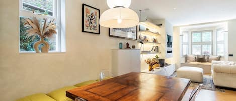 A modern dining area with a wooden table, chairs, and a hanging light fixture.